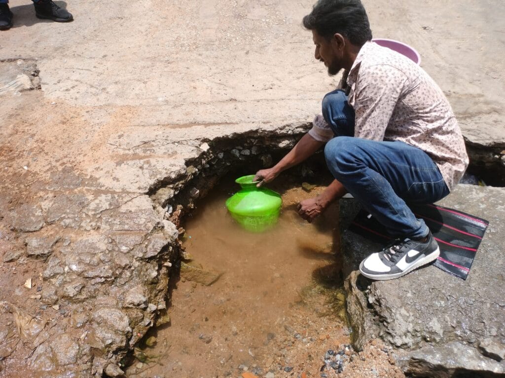 man filling water from a puddle