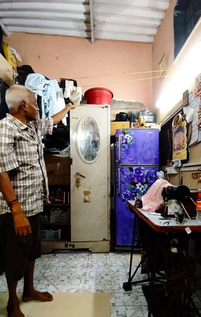 Ramesh Waghela pointing to how he keeps his belongings in the room during monsoon.