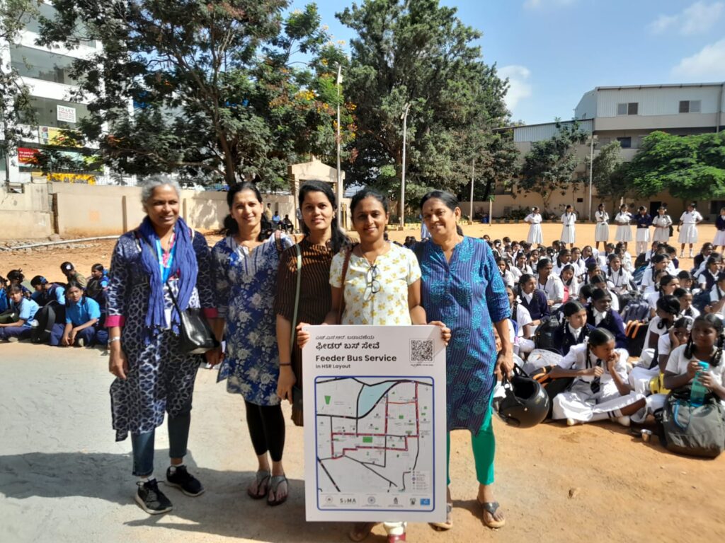 A group of ladies holding up the Feeder bus route map at a  school in Agara.
