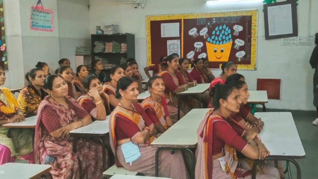Women members sitting at desks in a school for a work-related training during their employment at the school.